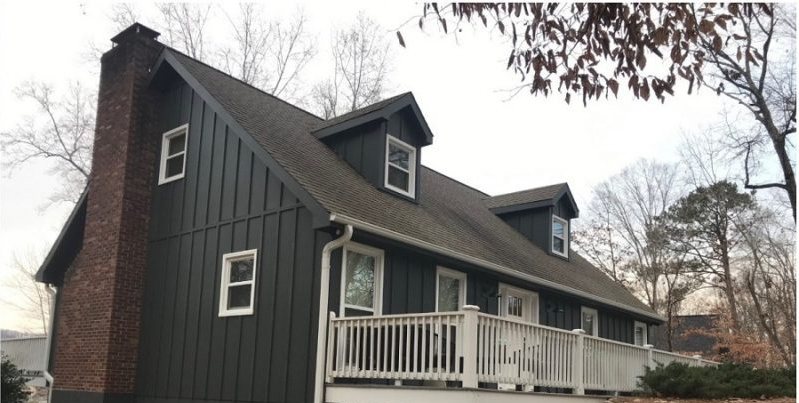 After: the same elevation in dark board-and-batten with the brick chimney left exposed.