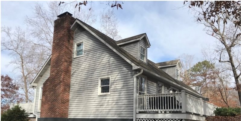 Before: a gambrel-roofed lake house in white lap siding with a lattice skirt and a brick chimney.