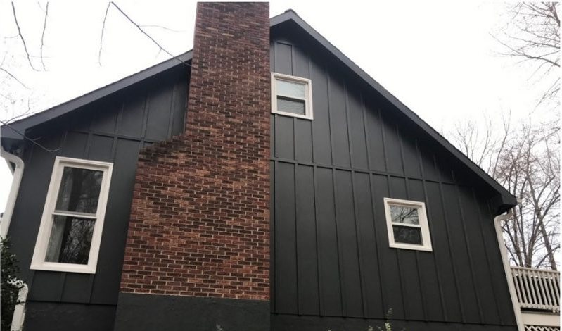 After: dark board-and-batten siding with the original red brick chimney left exposed.