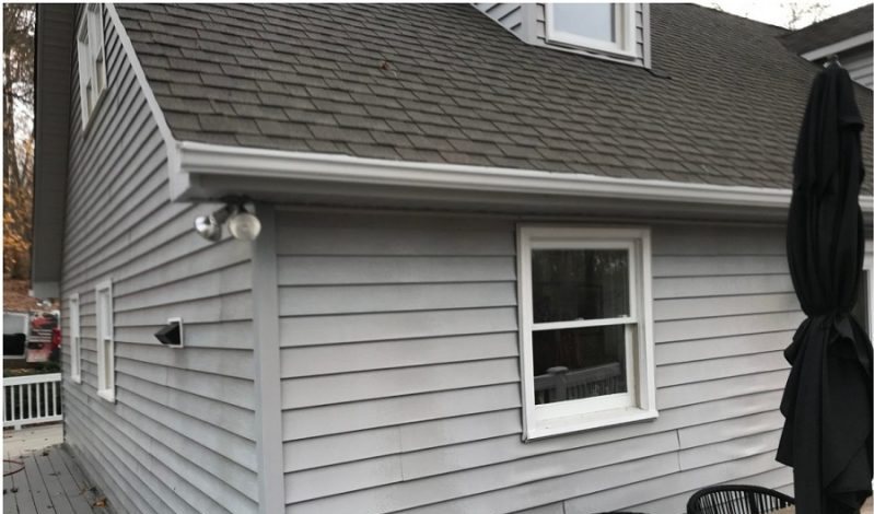 Before: white lap siding with a lattice skirt and a patio umbrella against the wall.