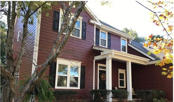 After: the same colonial in deep red Hardie Plank with bright white trim and a wreath on the door.