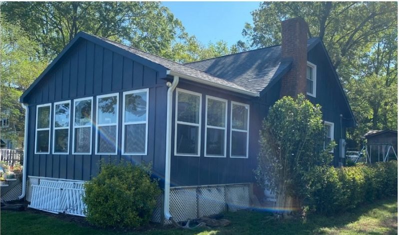 After: the finished room in deep navy siding with white window frames.