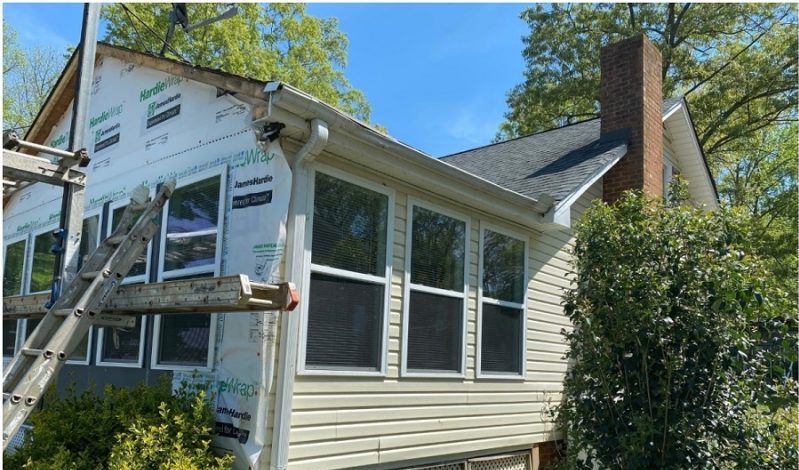 Before: the pale sunroom wall with weather barrier exposed and a boom lift alongside it.