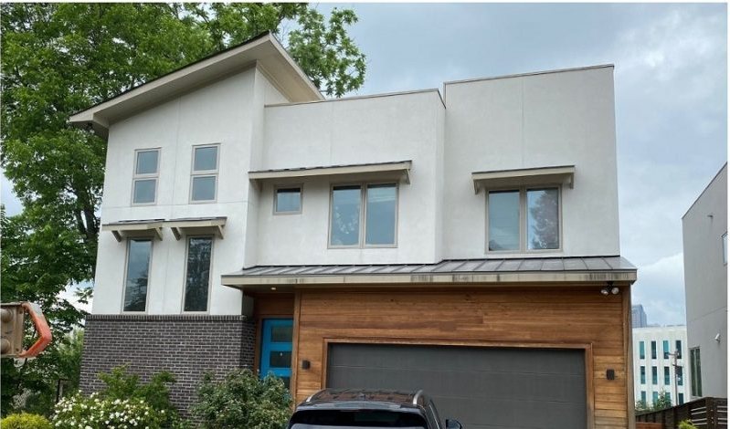 After: the same frontage with a timber-clad garage bay, a metal awning over the windows and planted beds.