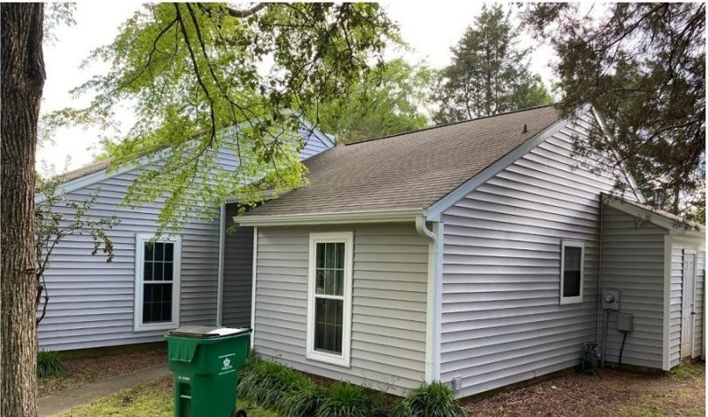 After: the same elevation in fresh pale siding with new trim around the window.