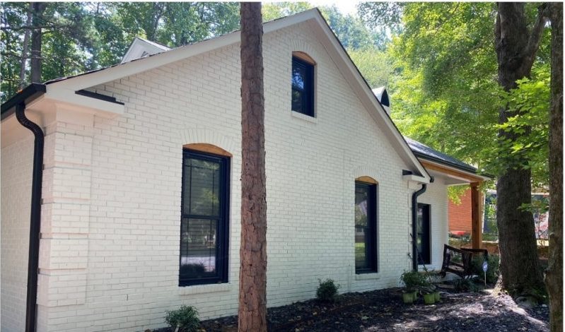 After: the same home with the brick painted soft white, new trim and replacement windows.