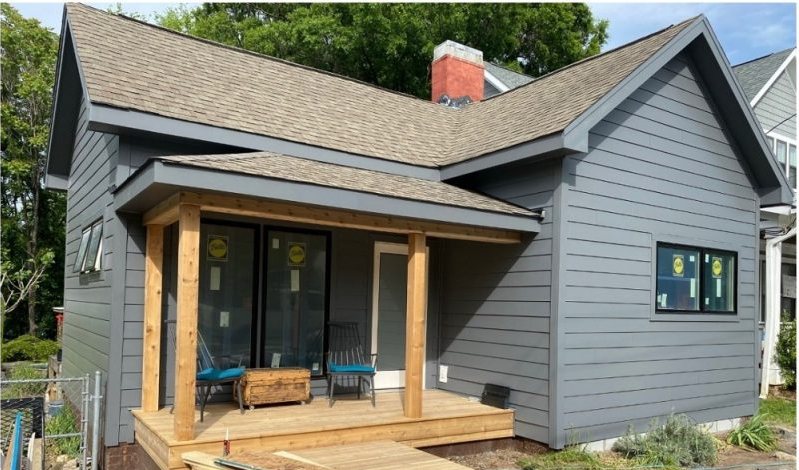 After: the same bungalow in gray siding with a new cedar-post porch and a timber deck.
