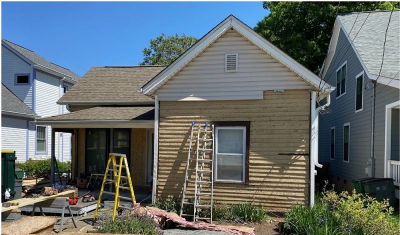 Before: a bungalow mid-job with bare sheathing, plywood on the ground and a ladder at the eaves.