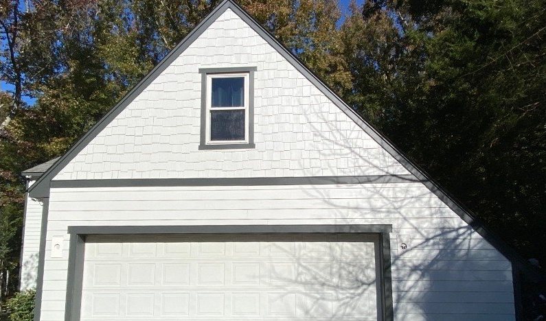 After: the same gable in clean white siding with new soffits and gutters.