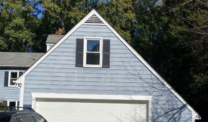 Before: a garage gable in gray siding with a truck parked hard against it.