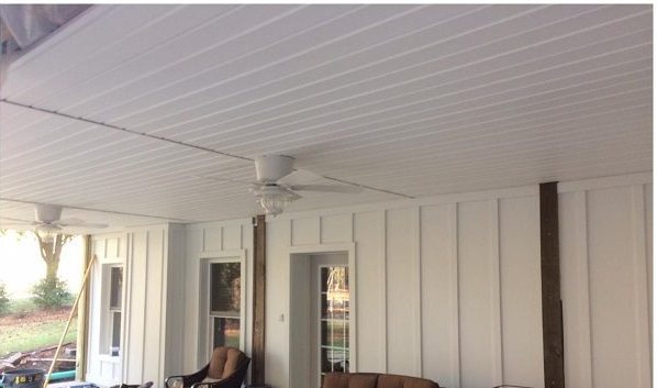 After: the same porch finished in white board-and-batten with a ceiling fan and furniture in place.