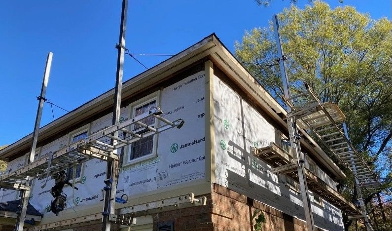 During: the corner of the house stripped back to weather barrier with scaffolding up.