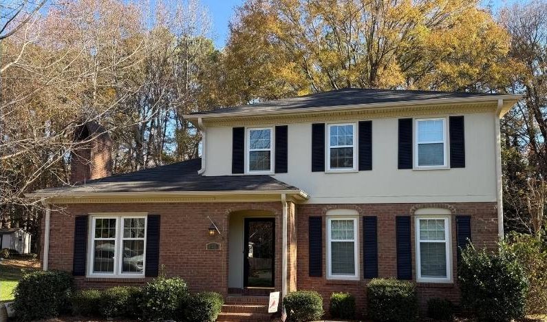 After: the finished house, cream siding above red brick with black shutters and a clear front walk.