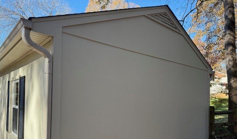 After: the same gable in clean pale siding with the streaking gone.