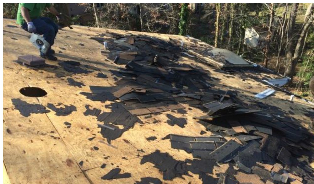 During: the roof stripped to bare decking with torn felt and a worker on the slope.
