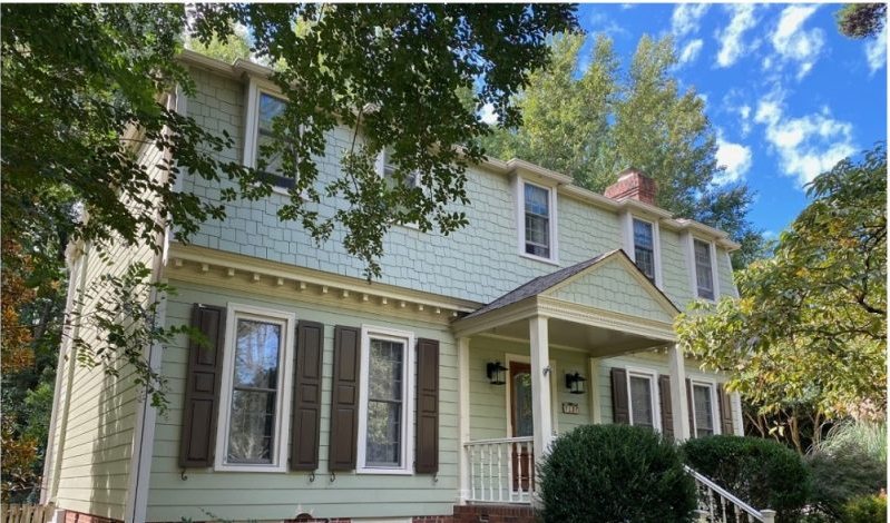 After: the same elevation in sage green lap siding with white trim and black shutters.