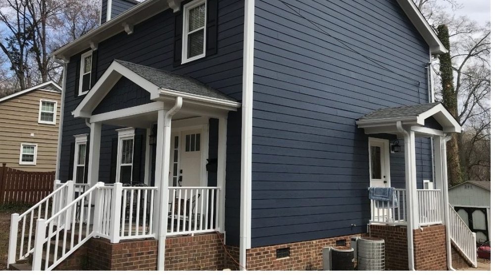 After: the same house in deep navy siding with crisp white porch rails and new steps.