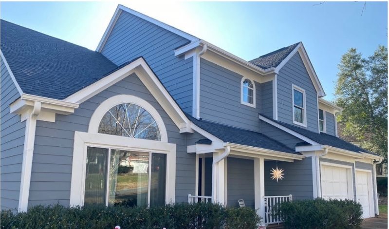After: the same house in blue-gray siding with white trim picking out the arched window.
