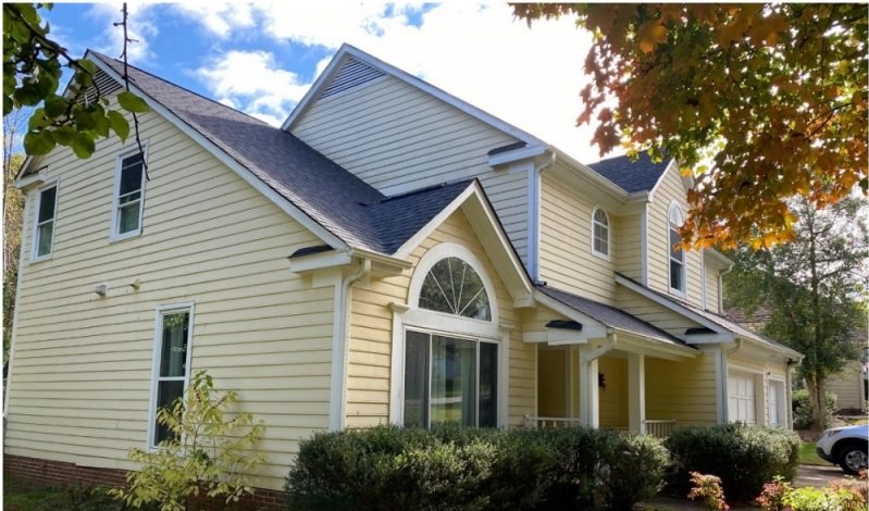 Before: a cream two-story with a tall arched feature window and dated trim.