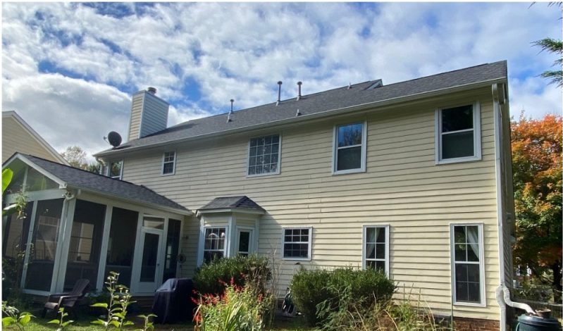 Before: the rear elevation in cream with an overgrown bed and a screened porch to one side.