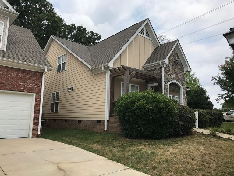 A brick and cedar-shake home at River Run in Davidson with its newly completed architectural shingle roof, seen from the driveway.