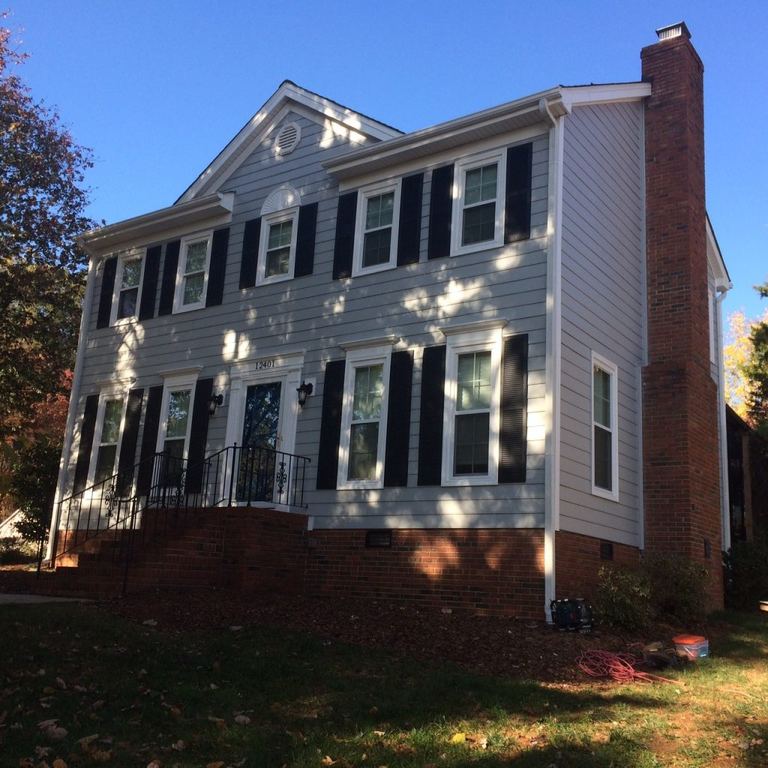 Gray two-story colonial with black shutters and white replacement windows