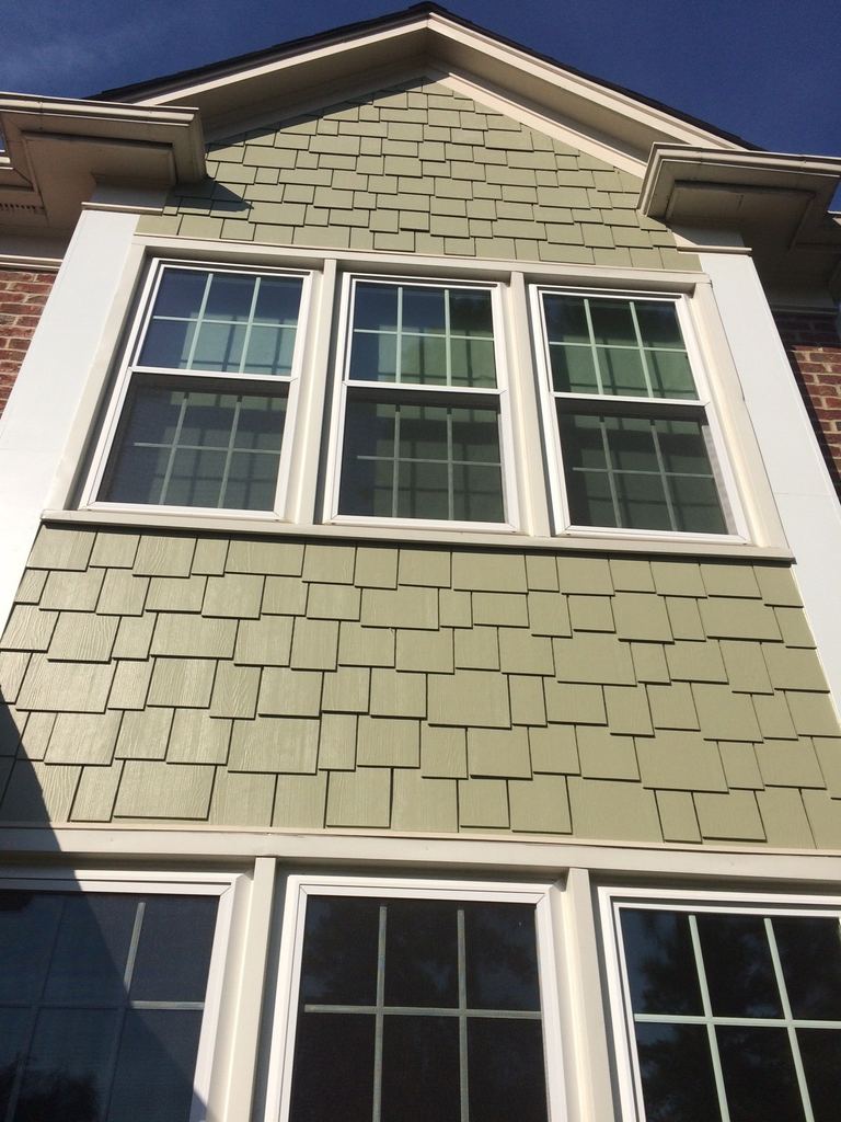 Staggered shingle-style siding above a bank of white replacement windows