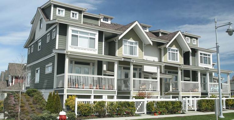 Multi-family building with gray siding, white trim and stacked balconies