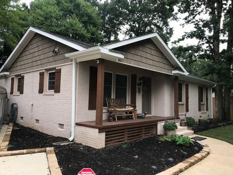 White painted brick bungalow with a covered front porch and new gutters