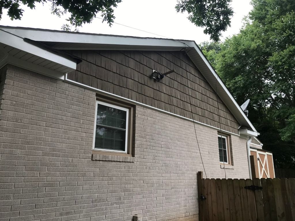 Gray shake-style siding in the gable above a painted white brick wall