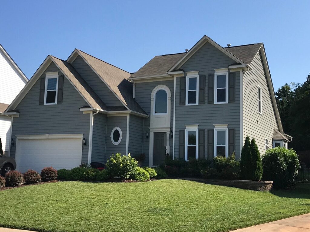 Blue-gray vinyl siding with white trim on a two-story home with an arched window