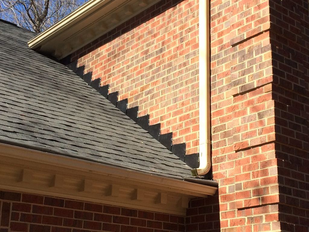 New shingle roof line meeting a brick wall with dentil trim detail