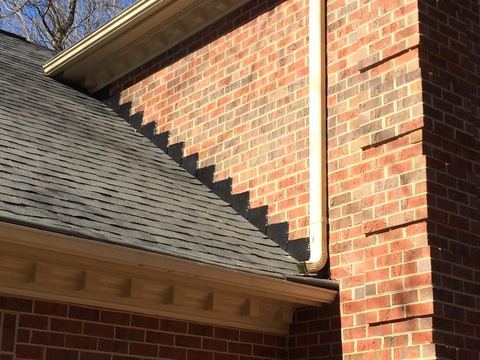 New shingle roof line meeting a brick wall with dentil trim detail