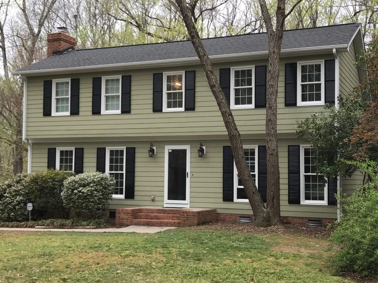 Sage green siding, white trim and black shutters on a completed two-story colonial