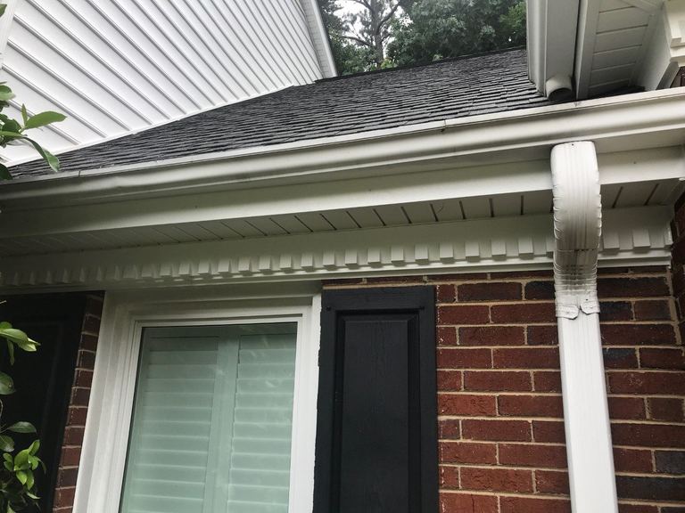 White exterior trim and molding where siding meets brick beside a downspout