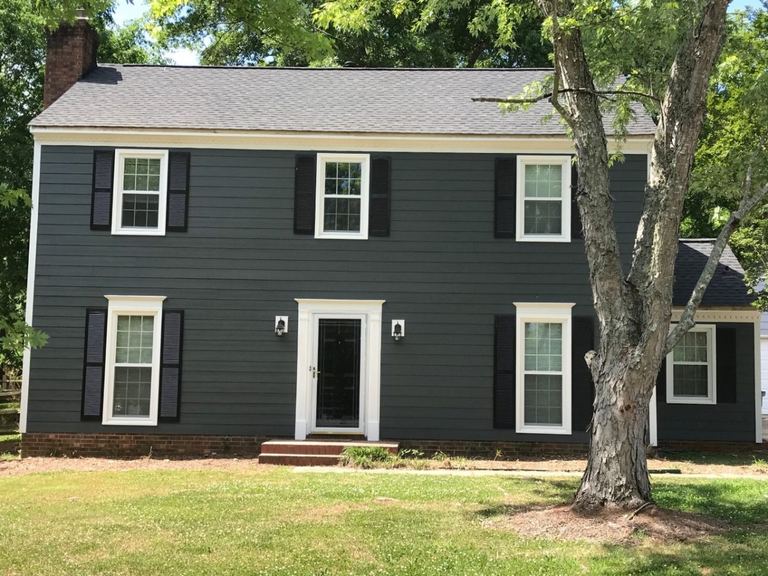 Dark gray lap siding with white window headers and trim on a two-story home