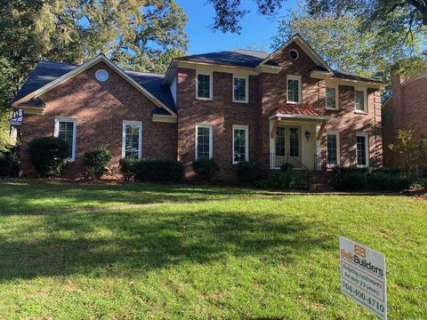Red brick two-story home with copper roof accents over the entry