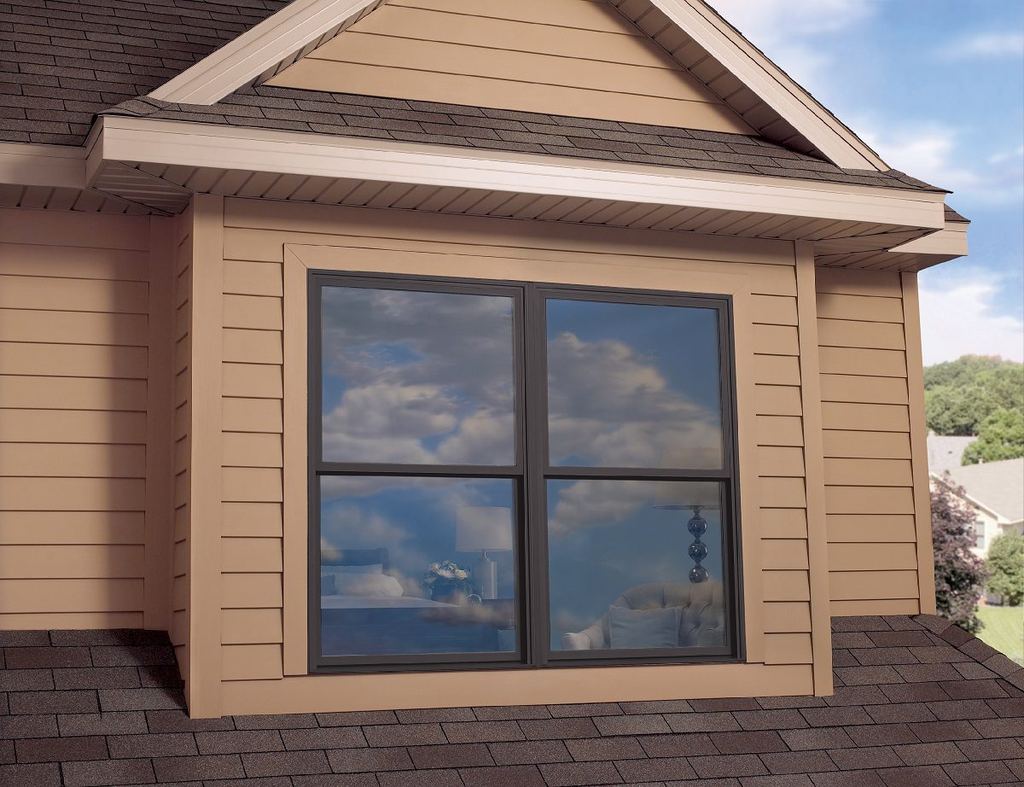 Tan-sided bay with a window reflecting the sky above a shingle roof