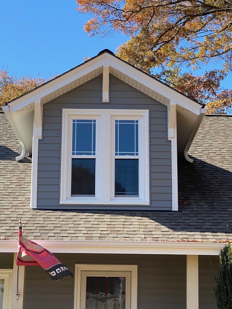 Blue-gray siding and a trio of white replacement windows in a gable end