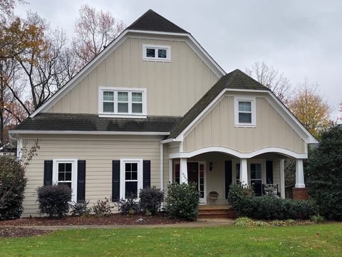 Tan fiber cement siding with black shutters on a craftsman-style home