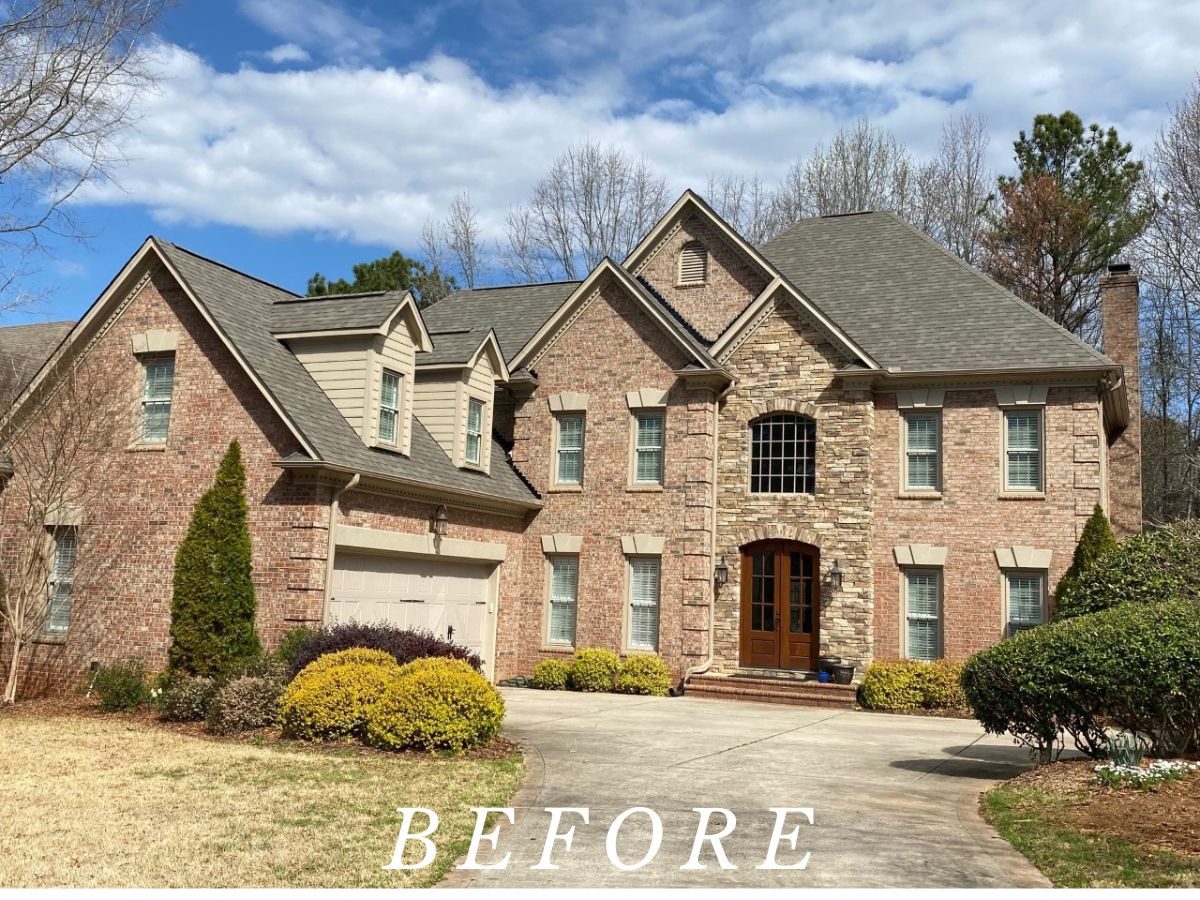 Before: a brick two-story home in Huntersville with bare windows and no shutters.
