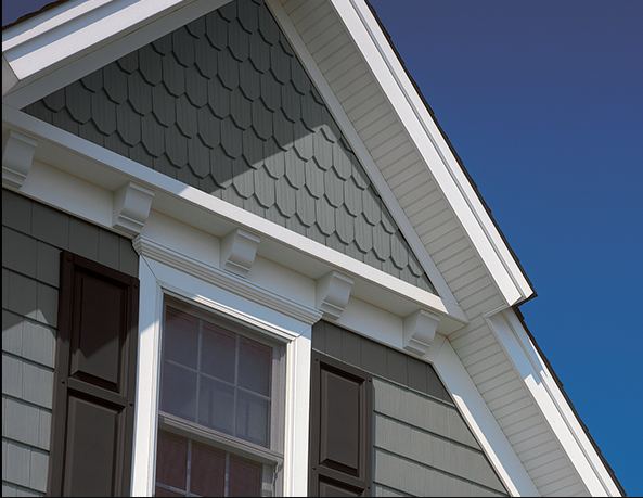 Scalloped shake-style polymer siding in a gable above a white-trimmed window
