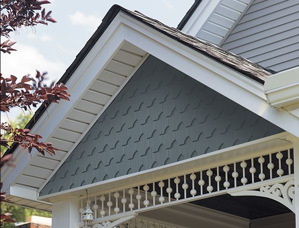 Dark gray shake-look polymer siding in a gable end with white trim and brackets