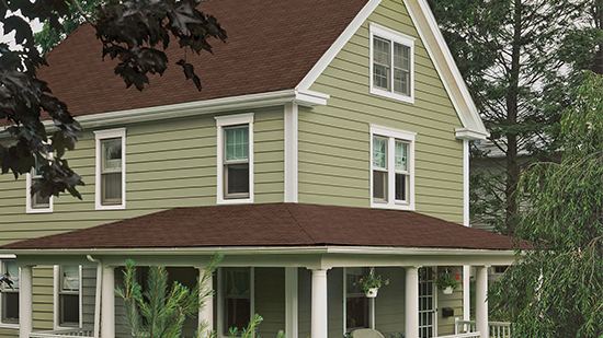Sage green siding with white window and corner trim on a two-story home