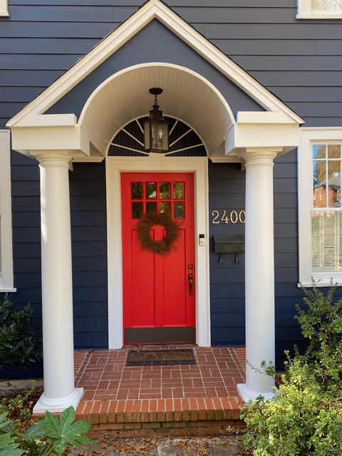 Navy fiber cement siding with a white portico and a red front door
