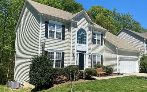 Cream insulated vinyl siding with white trim on a two-story home with an arched window