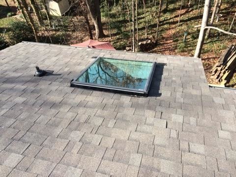 New shingle roof with a skylight on a wooded lot