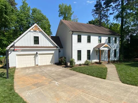 White two-story home with a board-and-batten gable and attached garage