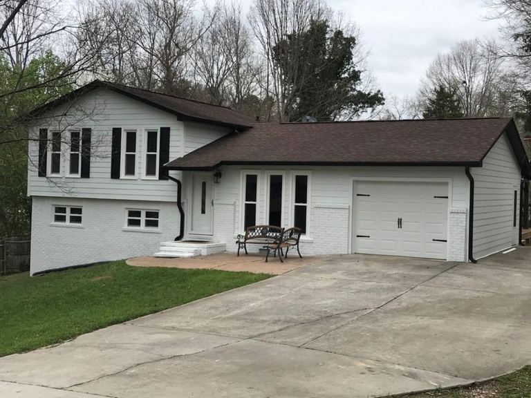White-sided split-level home with a brown roof and attached garage