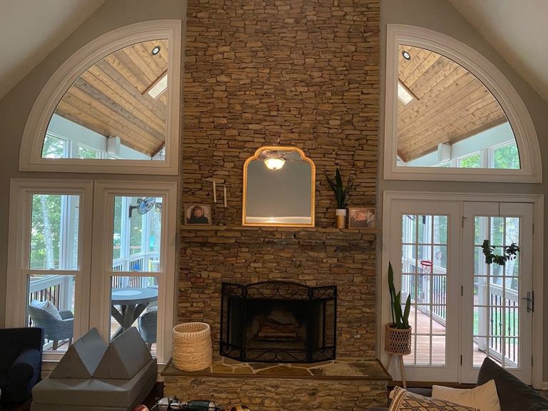 Interior great room with arched windows flanking a stone fireplace